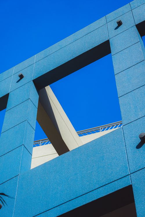 Free Dynamic view of a modern architectural structure with bright colors contrasting a clear blue sky. Stock Photo