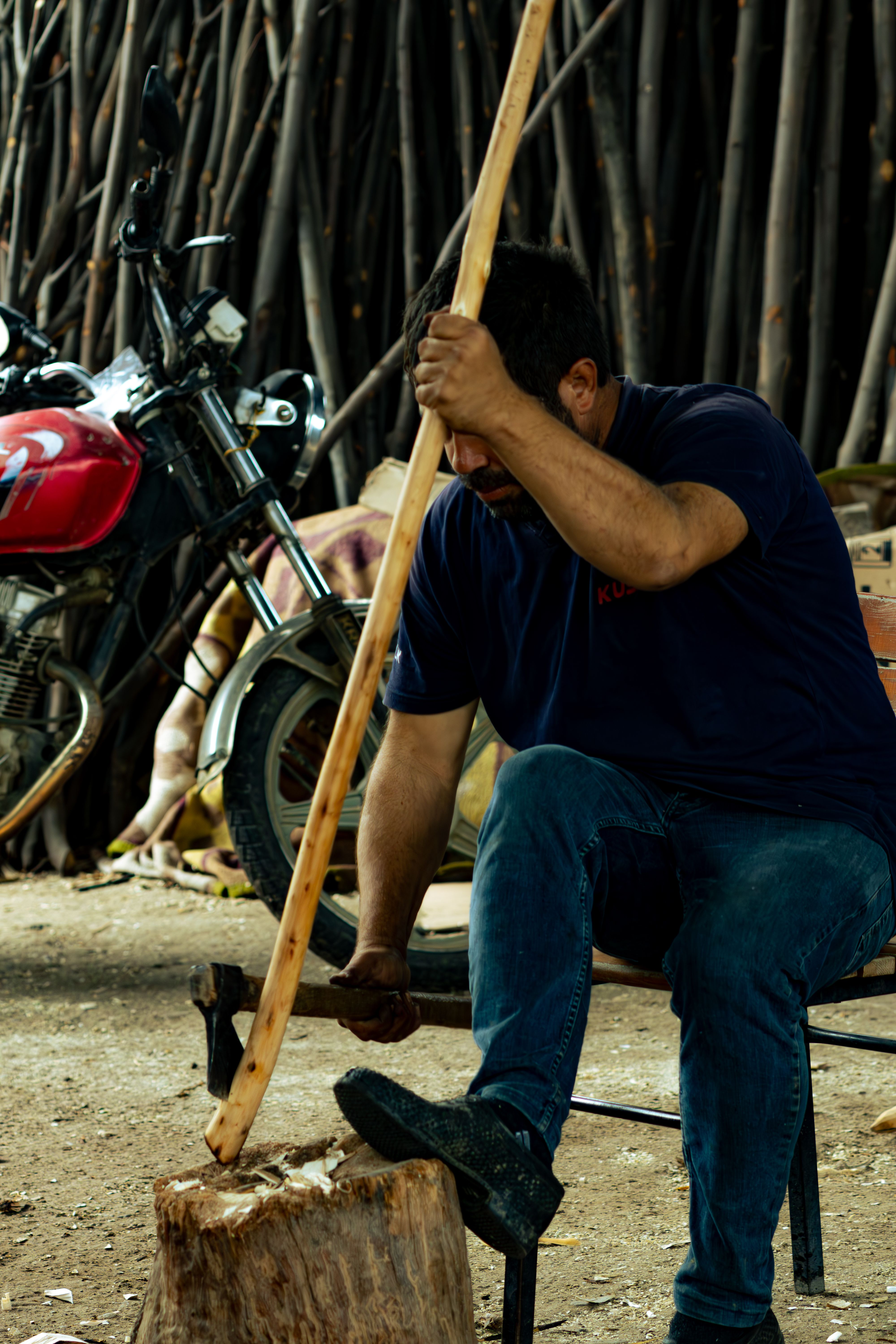 Skilled artisan carving wood with ax in rural Manisa setting, showcasing traditional craftsmanship.
