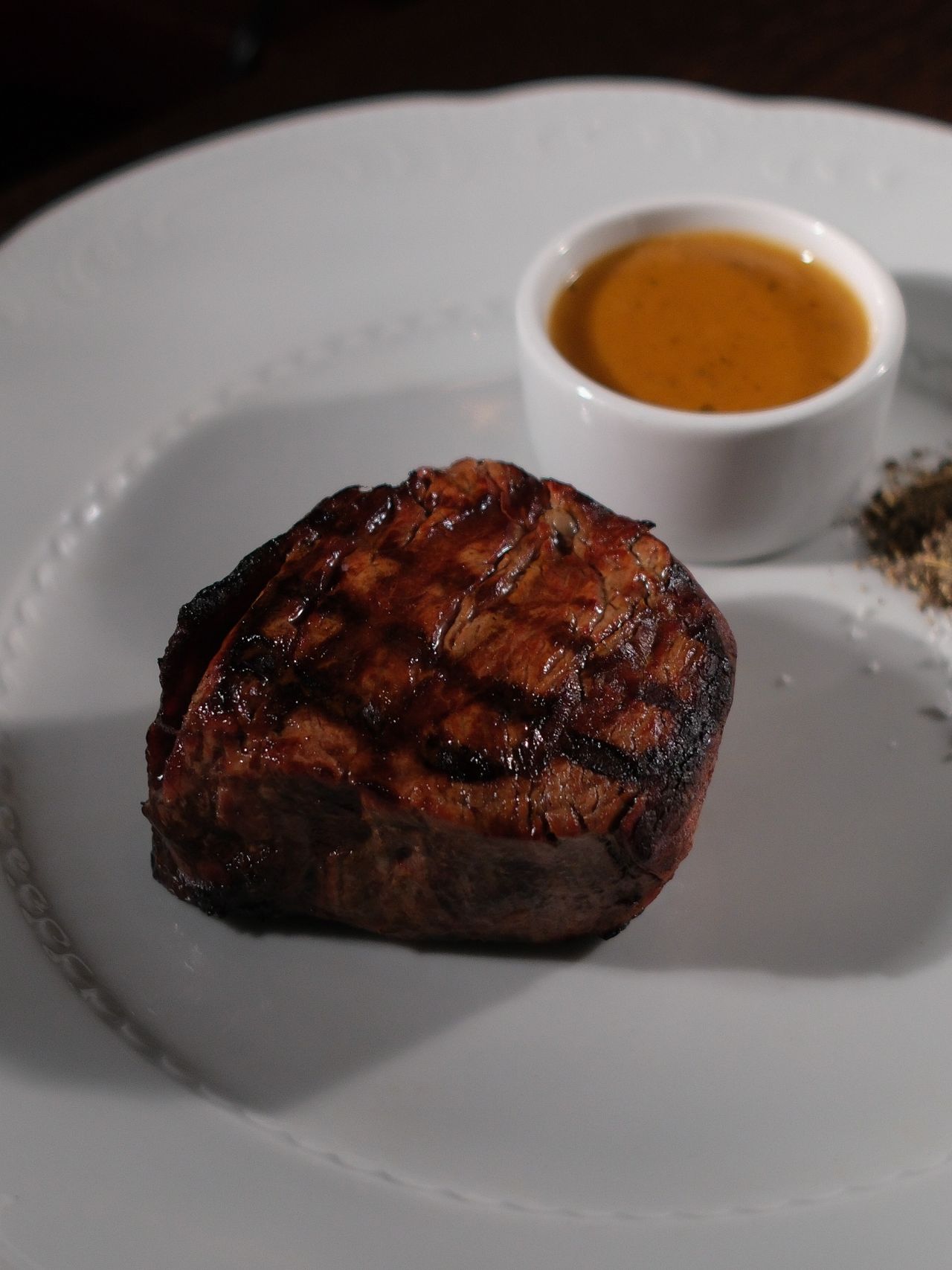 Grilled beef steak topped with a peppercorn cream sauce served on a white plate