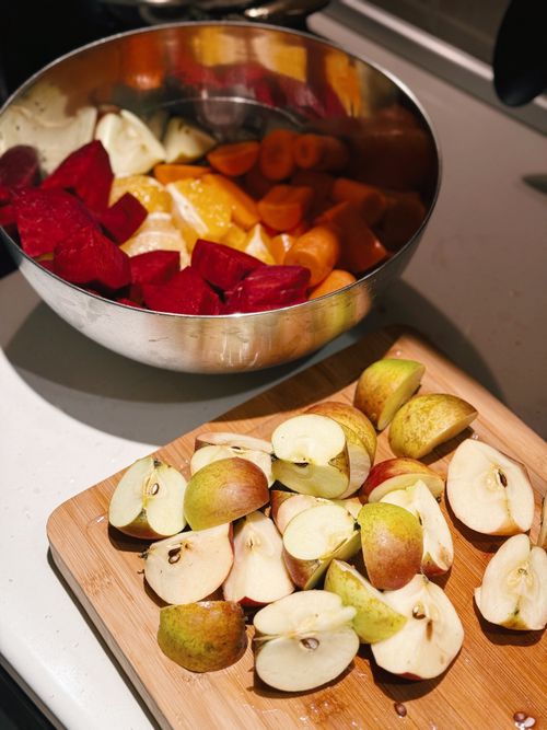Free Sliced apples, beets, carrots, and oranges prepared on a kitchen counter. Stock Photo