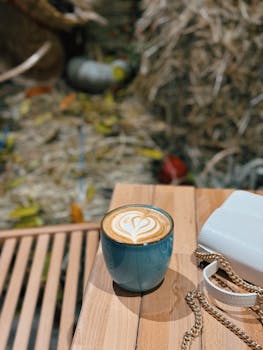 A cozy scene with a latte in a blue cup featuring a heart design on a wooden table.