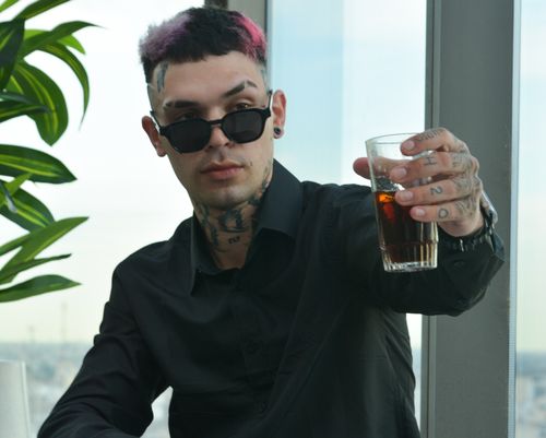Free Tattooed man wearing sunglasses raises a glass, adding a touch of urban sophistication indoors. Stock Photo