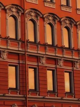 Warm sunset light on a detailed historical building facade with arched windows.