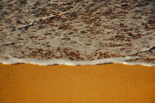 Free Golden sand meets gentle waves at sunset on a beach in Casablanca, Morocco. Stock Photo