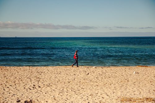 Free A lone man strolling on a Casablanca beach during sunset, capturing the serene ocean view. Stock Photo