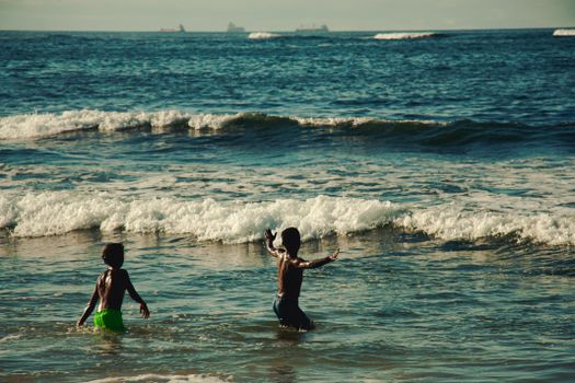 Two children enjoying the waves at a Moroccan beach in Casablanca.