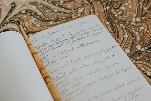 Open notebook with elegant calligraphy on a decorative background, featuring artistic handwriting.