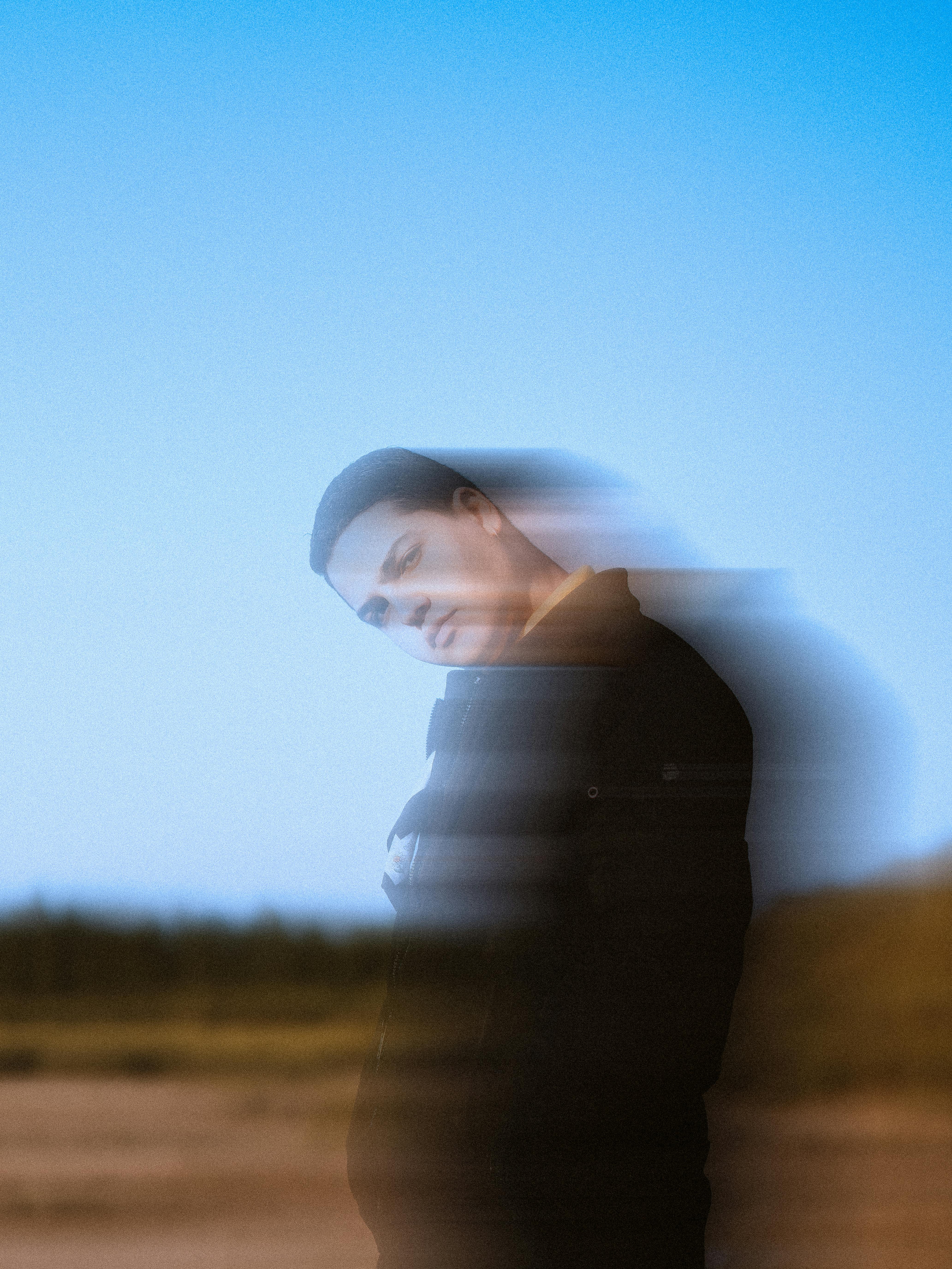 Artistic portrait of a person outdoors with motion blur effect, emphasizing movement and expression.