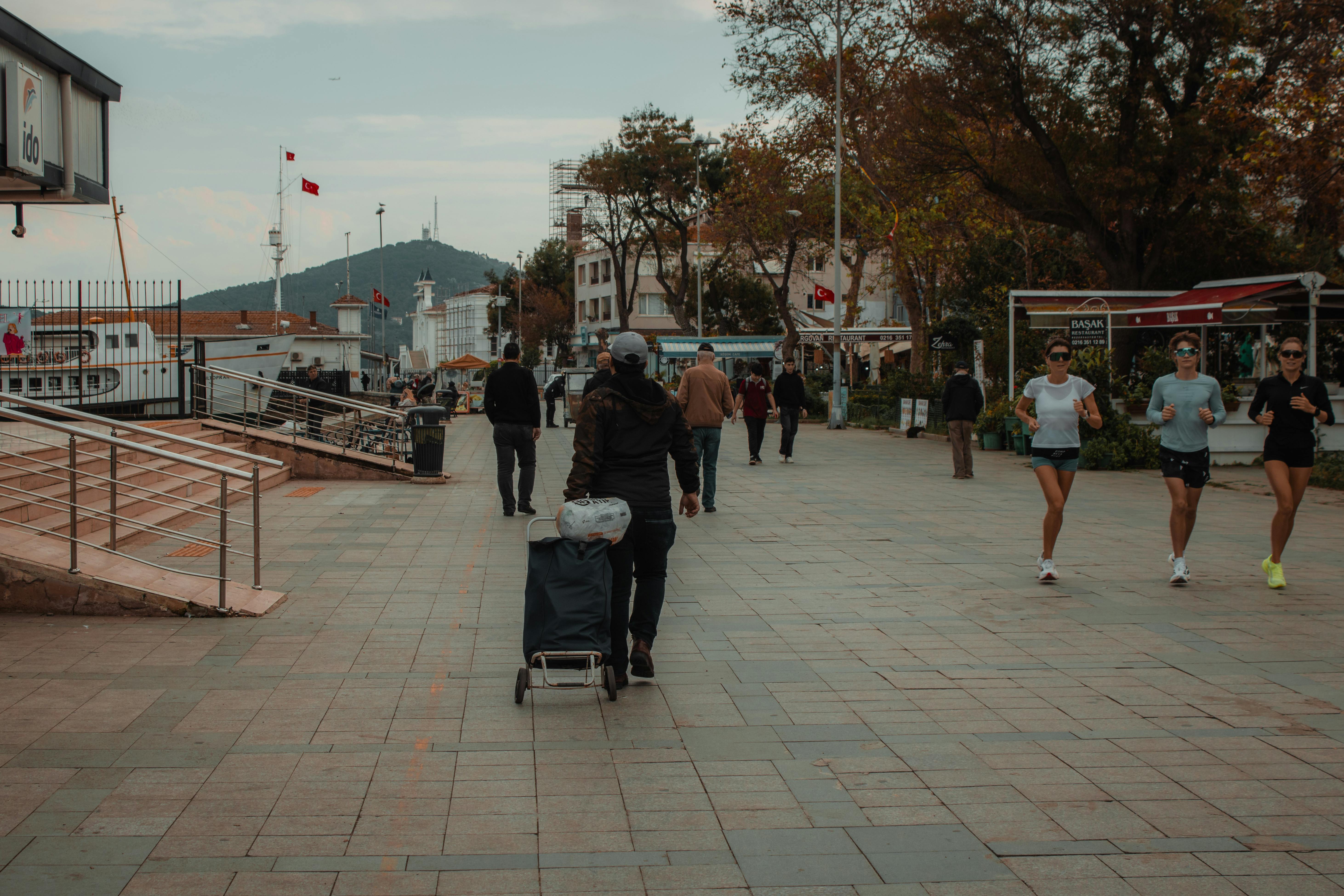 Lively street scene in Heybeliada, Turkey, featuring joggers and pedestrians on a bustling walkway.