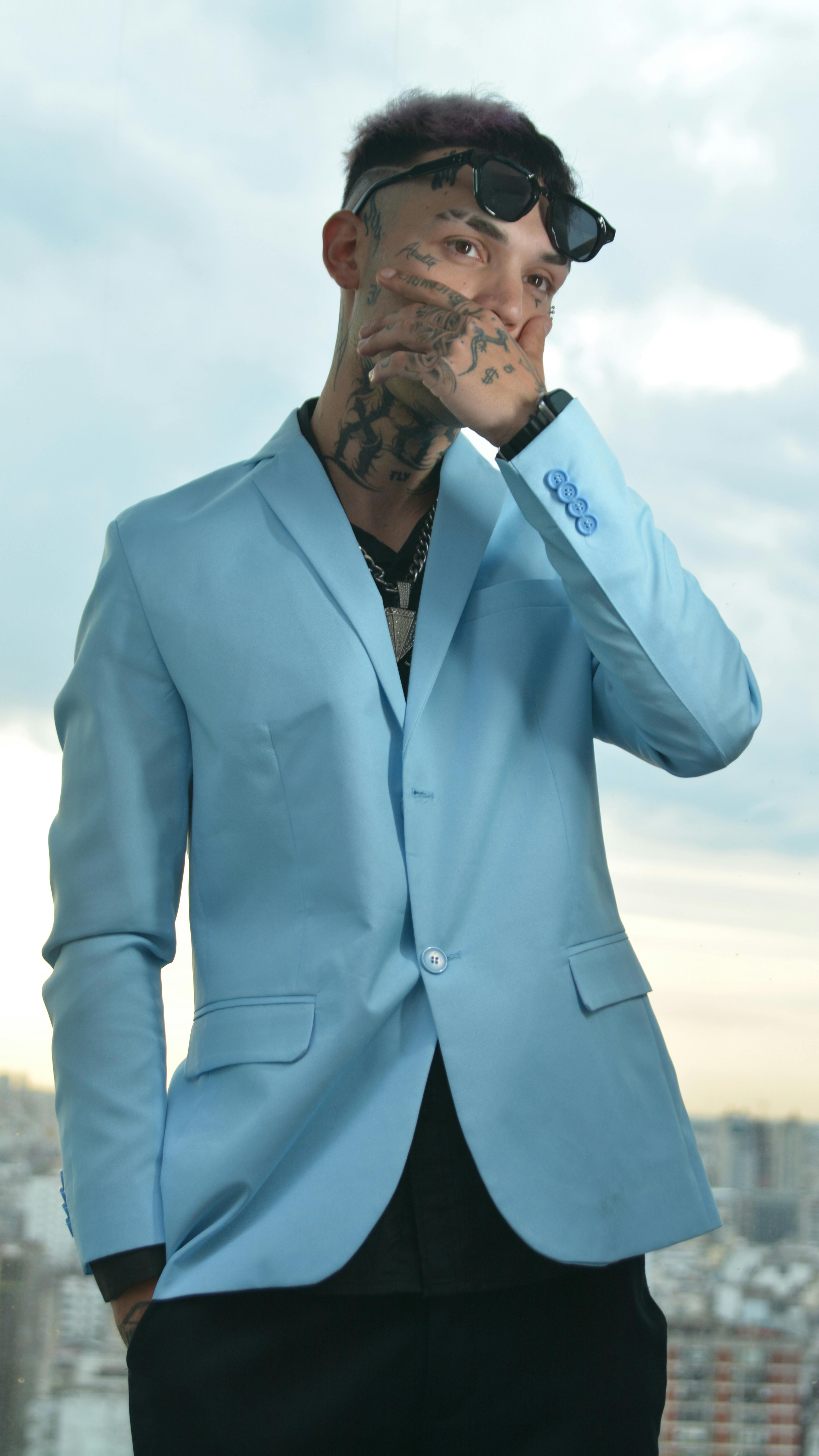 De franc Home tatuat de moda amb un vestit blau clar posant amb estil a l'aire lliure. Foto d'estoc