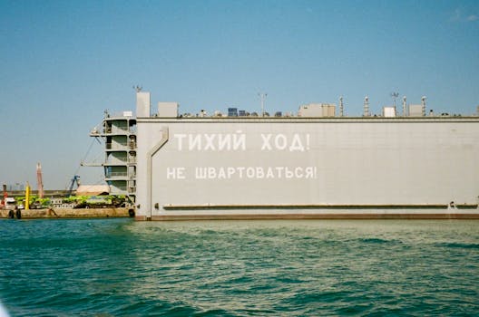Cargo ship at port with warning sign in Russian, calm sea.