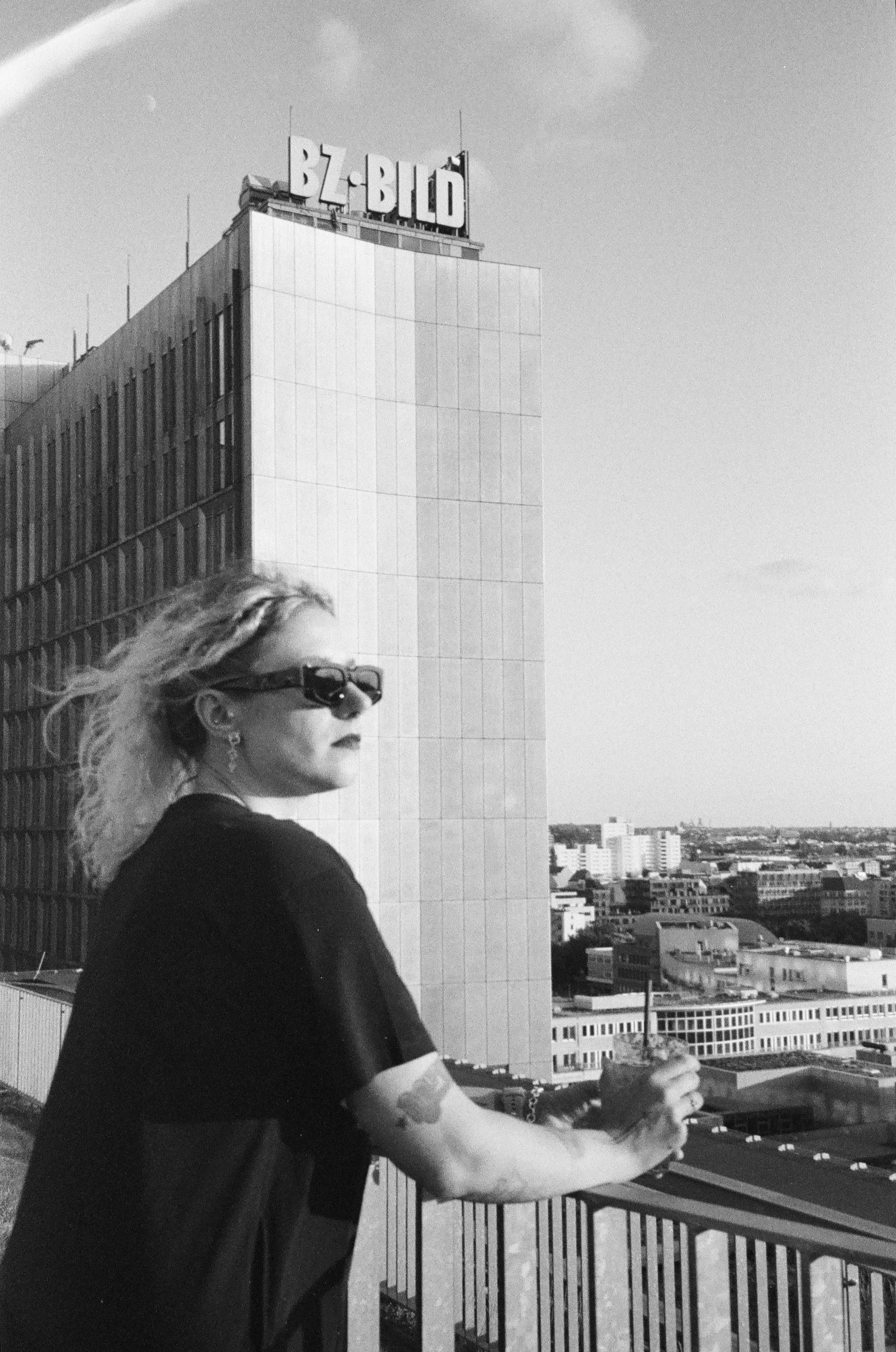 Black and white portrait of a woman overlooking a city from high vantage point.