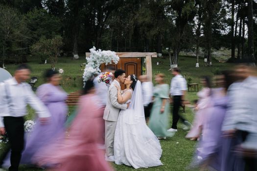 Bride and groom sharing a kiss amid dynamic motion at an elegant outdoor wedding ceremony.