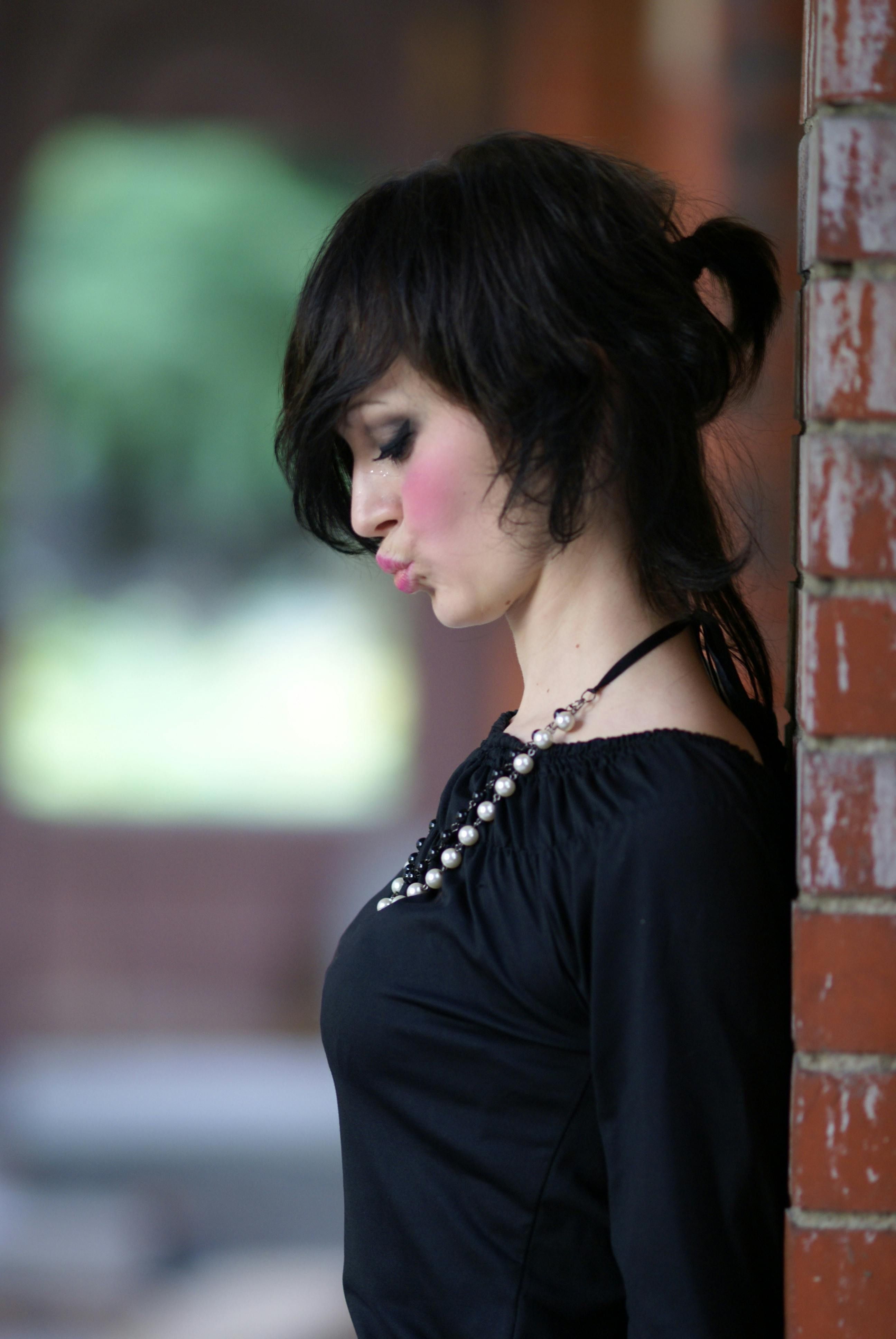 Pensive Woman Leaning Against a Brick Wall · Free Stock Photo