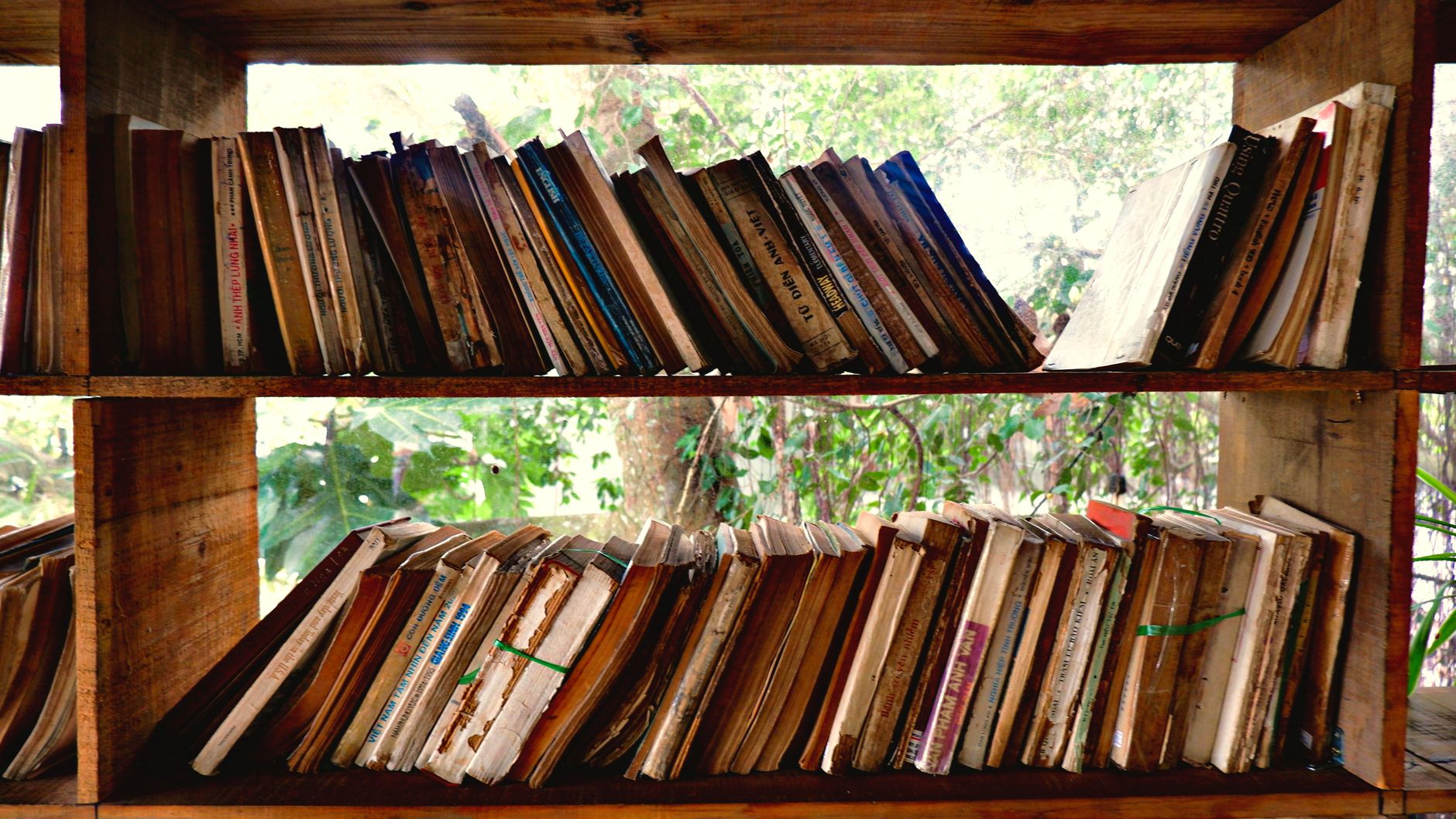 A rustic bookshelf in Vietnam filled with old, worn books, evoking nostalgia and history.