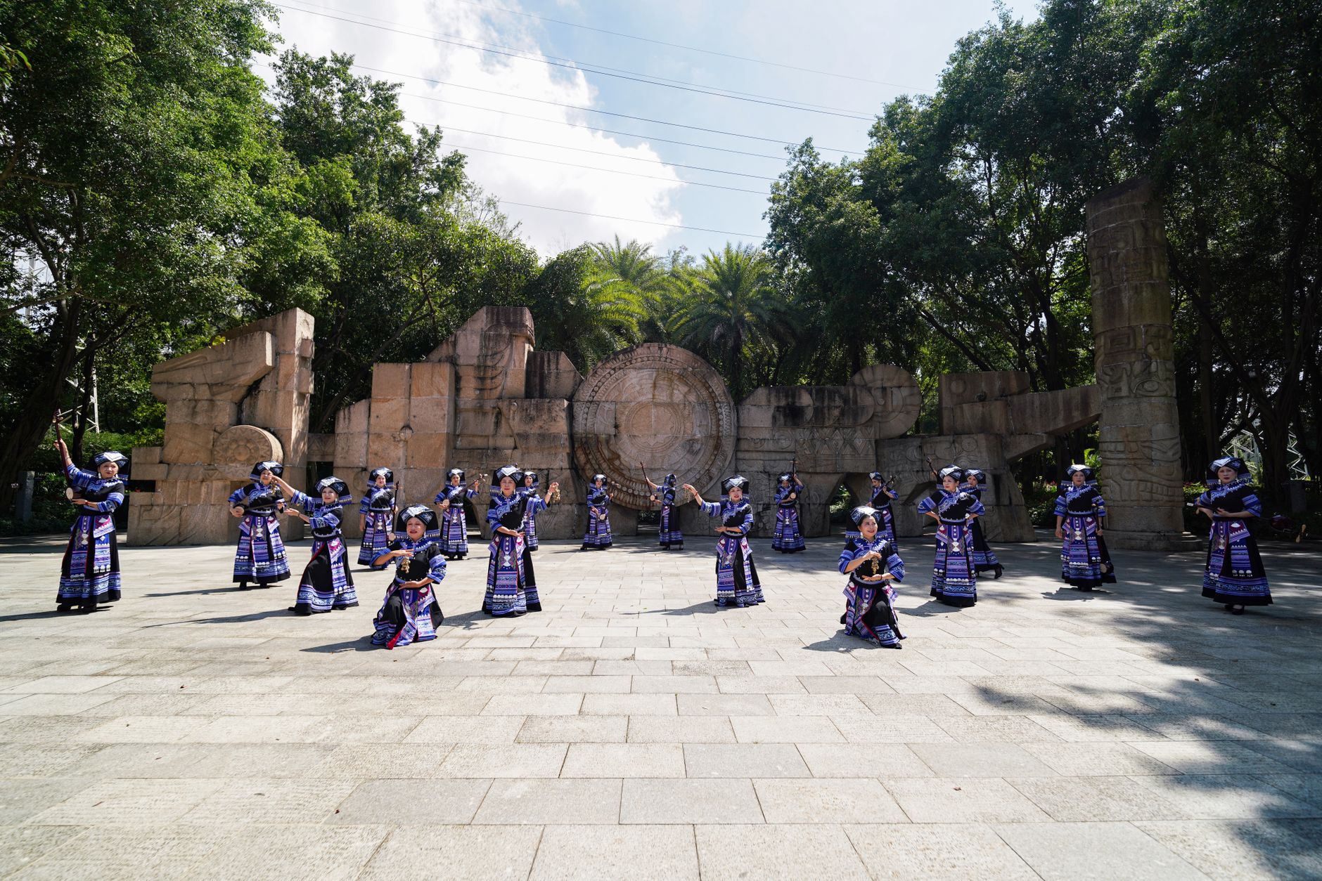 Zhuang performers in traditional costumes dance in an outdoor setting in Guangxi, China.