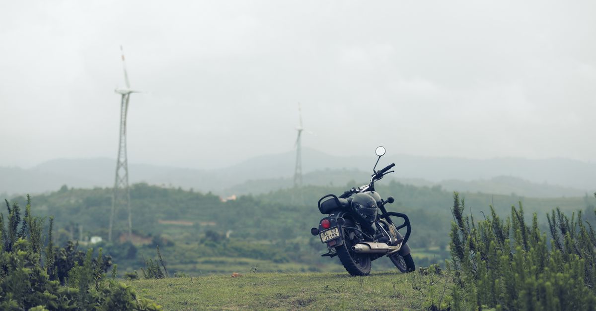 A traveler riding a bicycle through a scenic countryside with wind turbines in the background