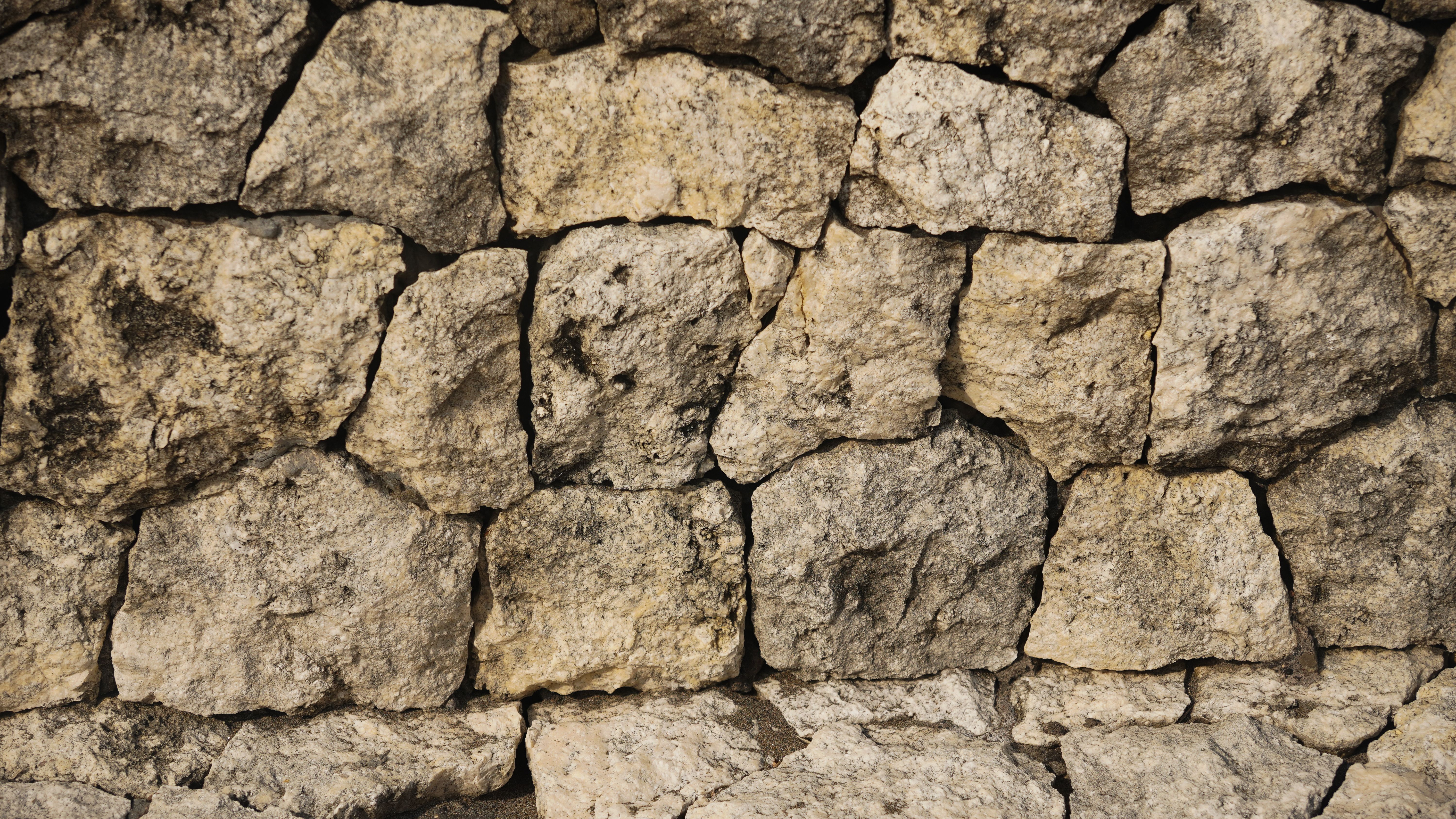Detailed close-up of a rustic stone wall with a rough texture and natural earthy tones.