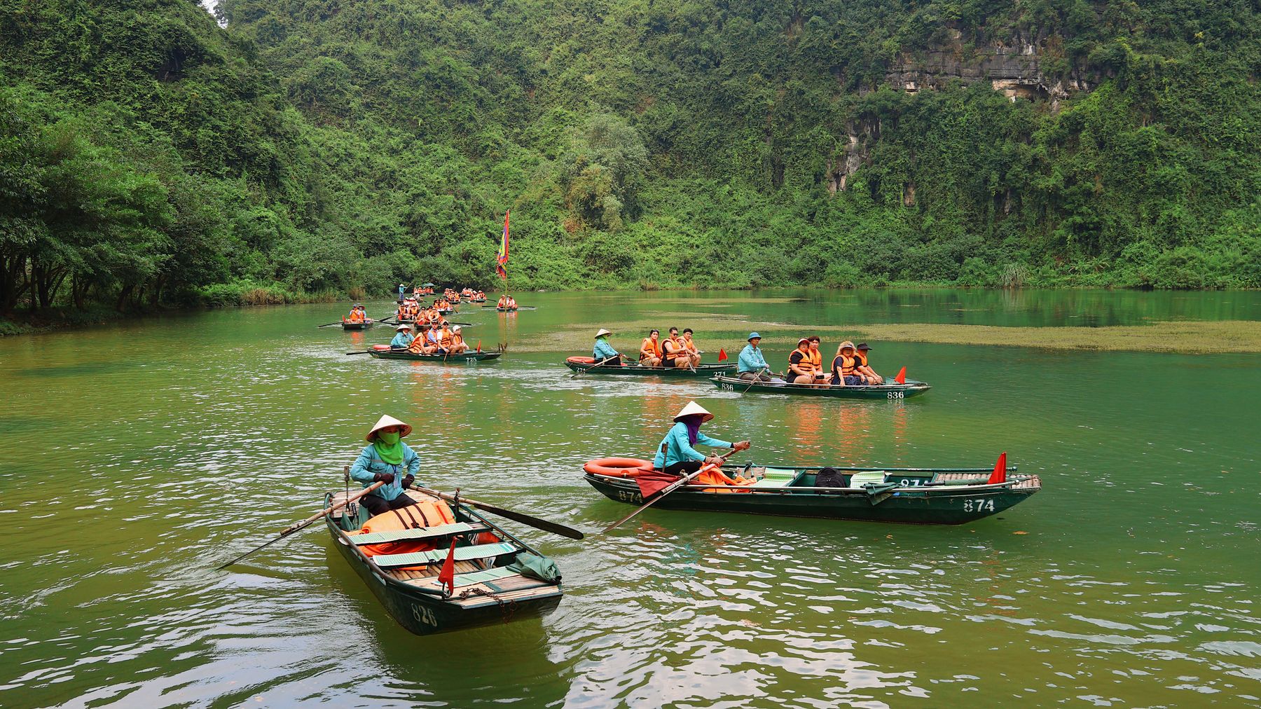 Tourists enjoy a traditional boat ride through the lush landscapes of Hoa LΖ°, Vietnam.