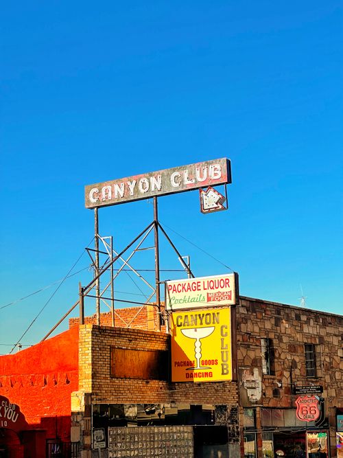 Free Canyon Club sign in Williams, AZ along historic Route 66 with vibrant blue sky backdrop. Stock Photo