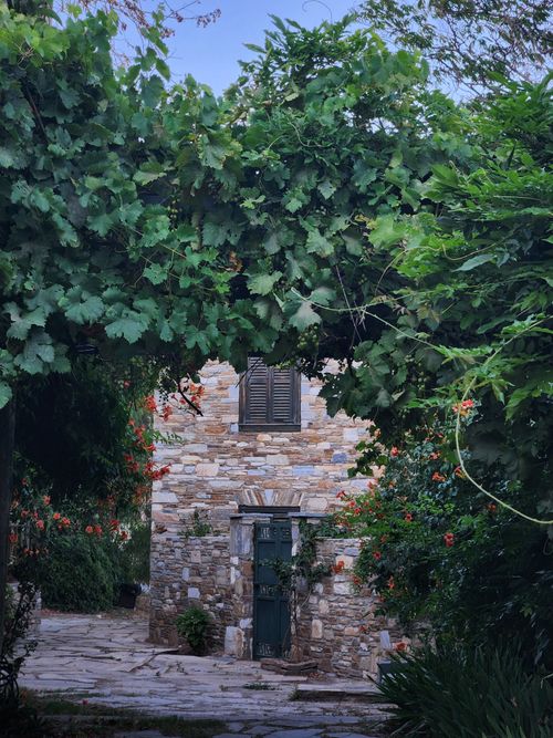 Free A picturesque stone house surrounded by lush greenery and vibrant flowers. Stock Photo