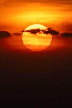 Captivating sunset with a vibrant orange sun and dark clouds.