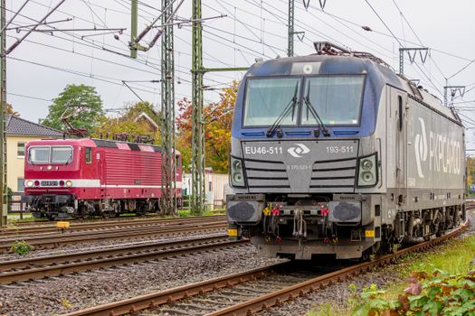 A modern and a vintage train stand side by side in a colorful rail yard in Niedersachsen, Germany.
