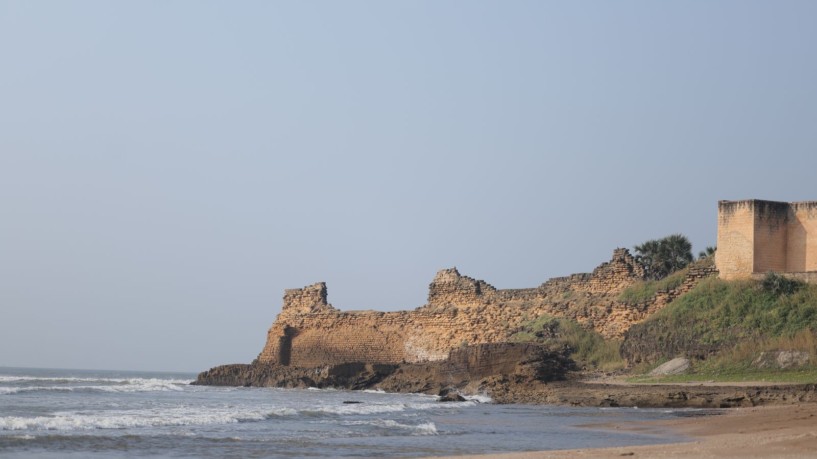 Ancient coastal fort ruins along scenic beach, Côte d'Ivoire