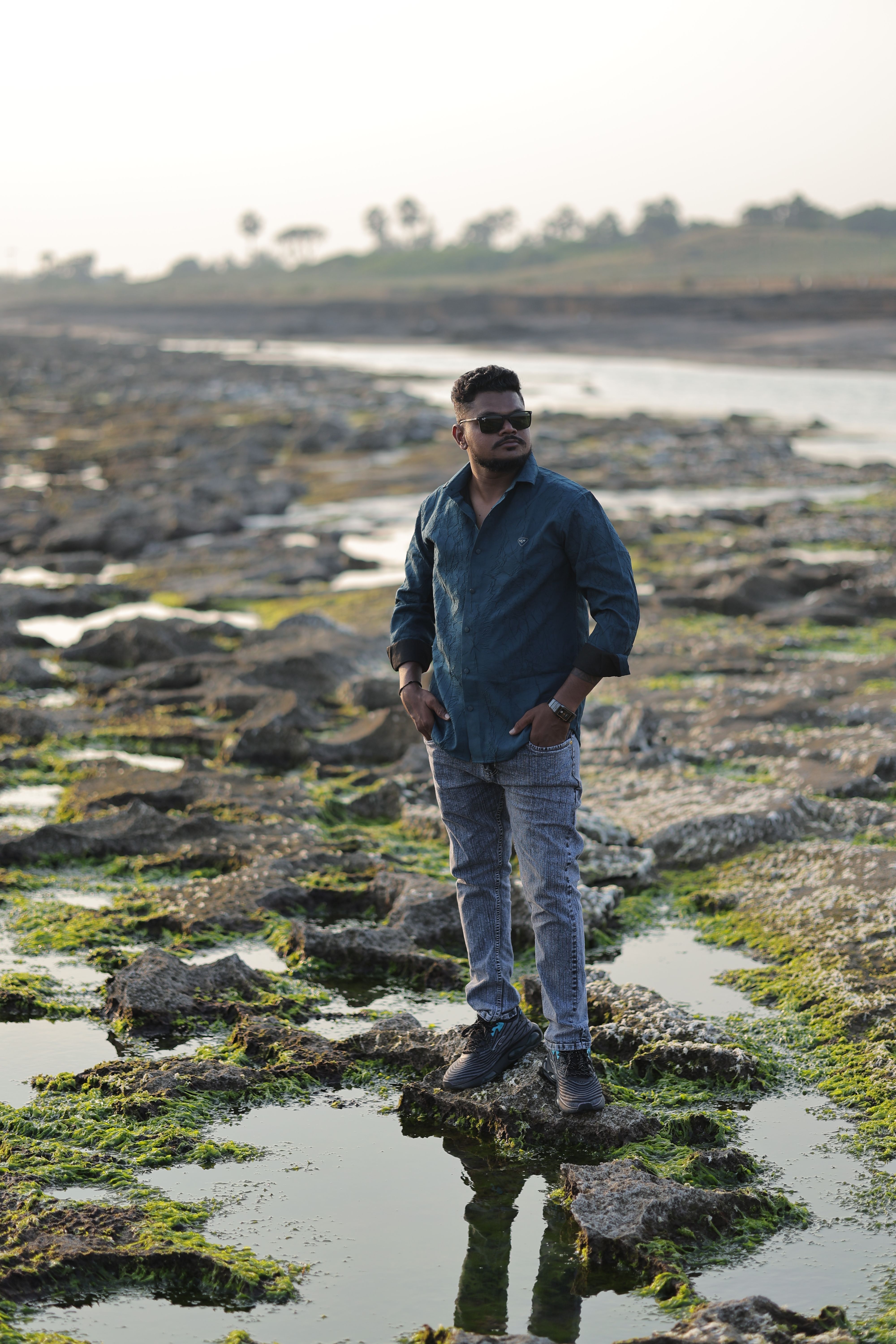 A man stands confidently on a rocky shore, reflecting the spirit of adventure.