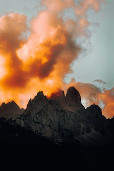 Stunning sunset over jagged peaks of the Austrian Alps with vibrant orange clouds.