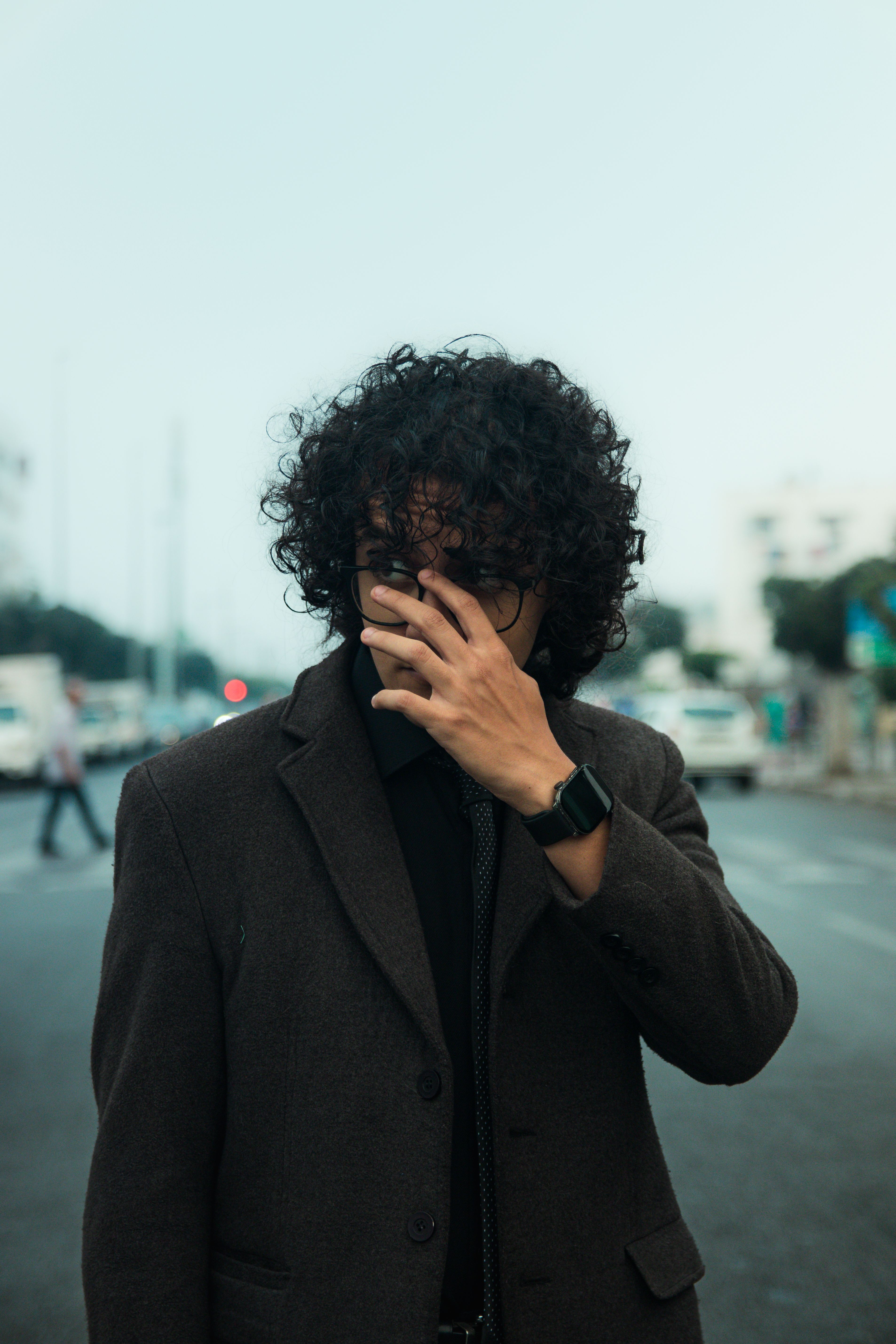 Curly-haired man in a suit covers his face in a busy street in Casablanca.