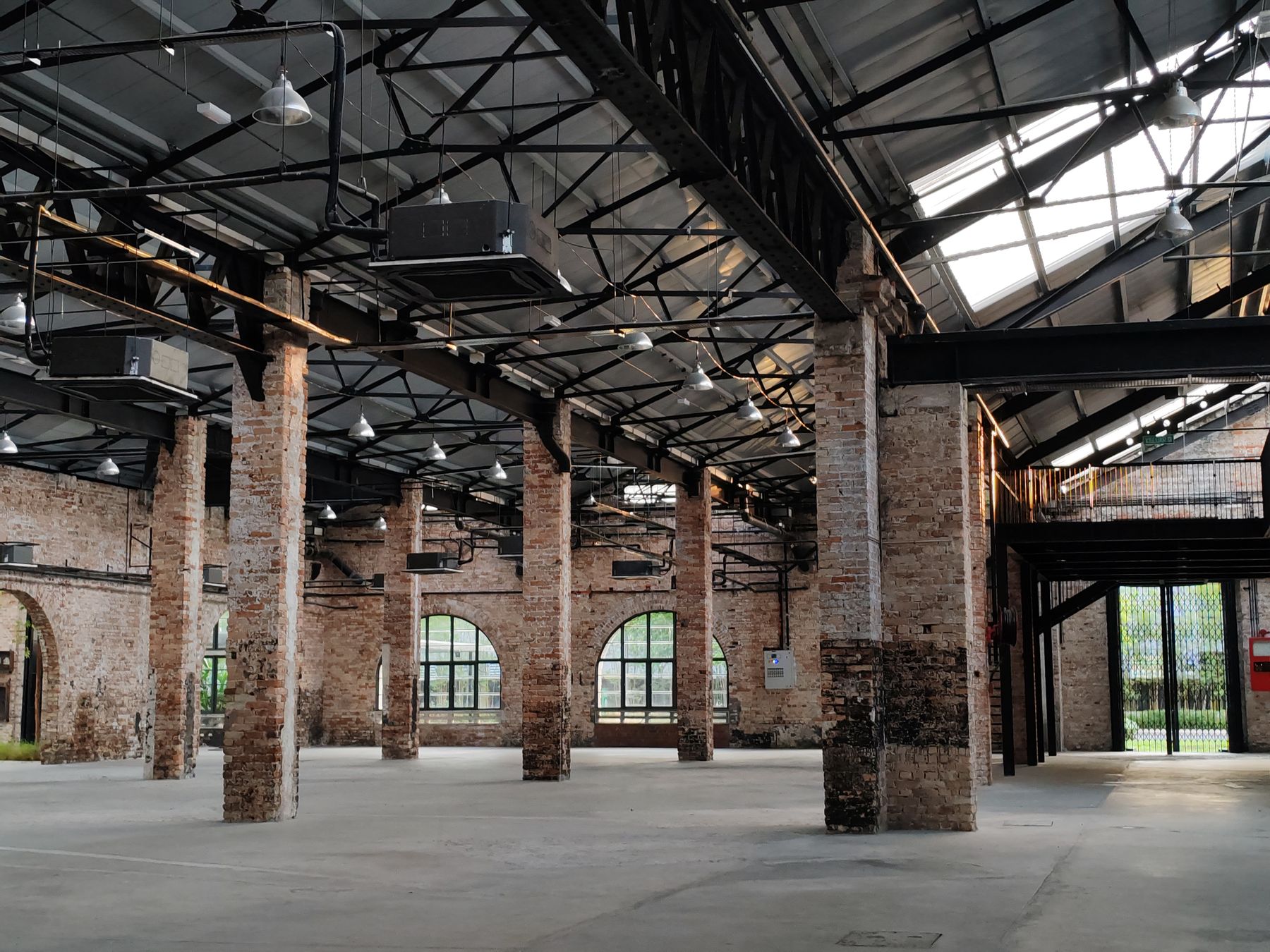 Spacious industrial warehouse interior with exposed brick walls, steel framing, high ceilings, and natural light.