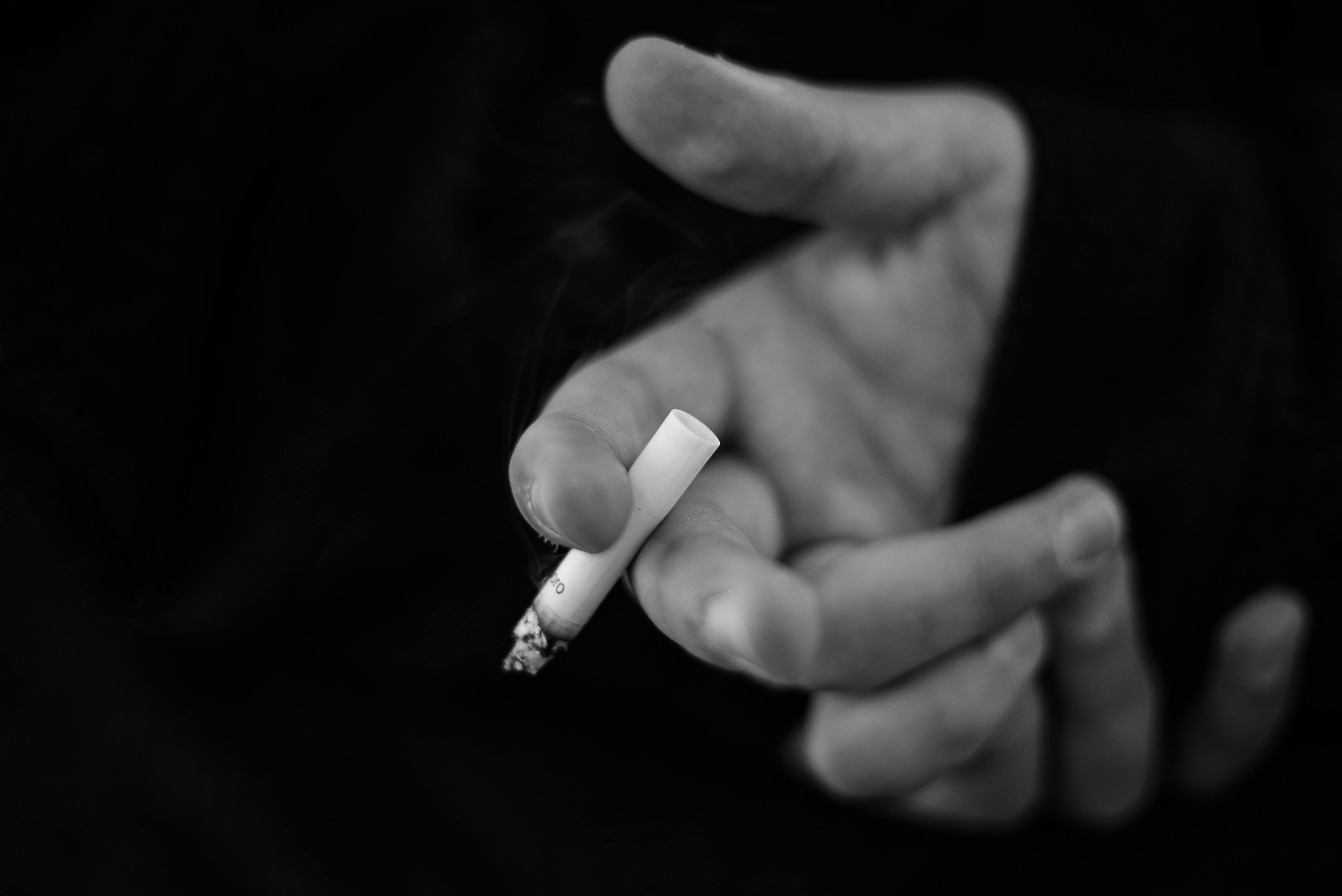 무료 담배를 쥔 손의 흑백 이미지로, 흡연 습관에 초점을 맞췄습니다. 스톡 사진