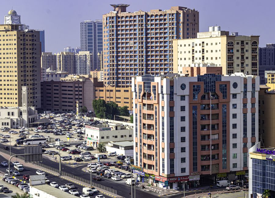 Aerial view of Ajman's urban skyline featuring highrise apartment buildings and busy streets.