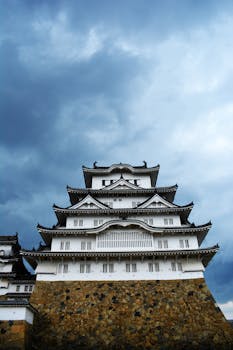 Himeji Castle's intricate architecture stands grandly beneath a dramatic cloudy sky.