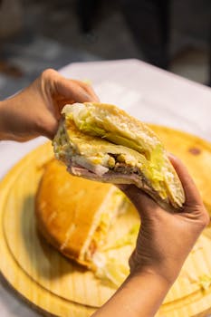 Close-up of hands holding a tasty sandwich filled with lettuce and meat, ready to eat.