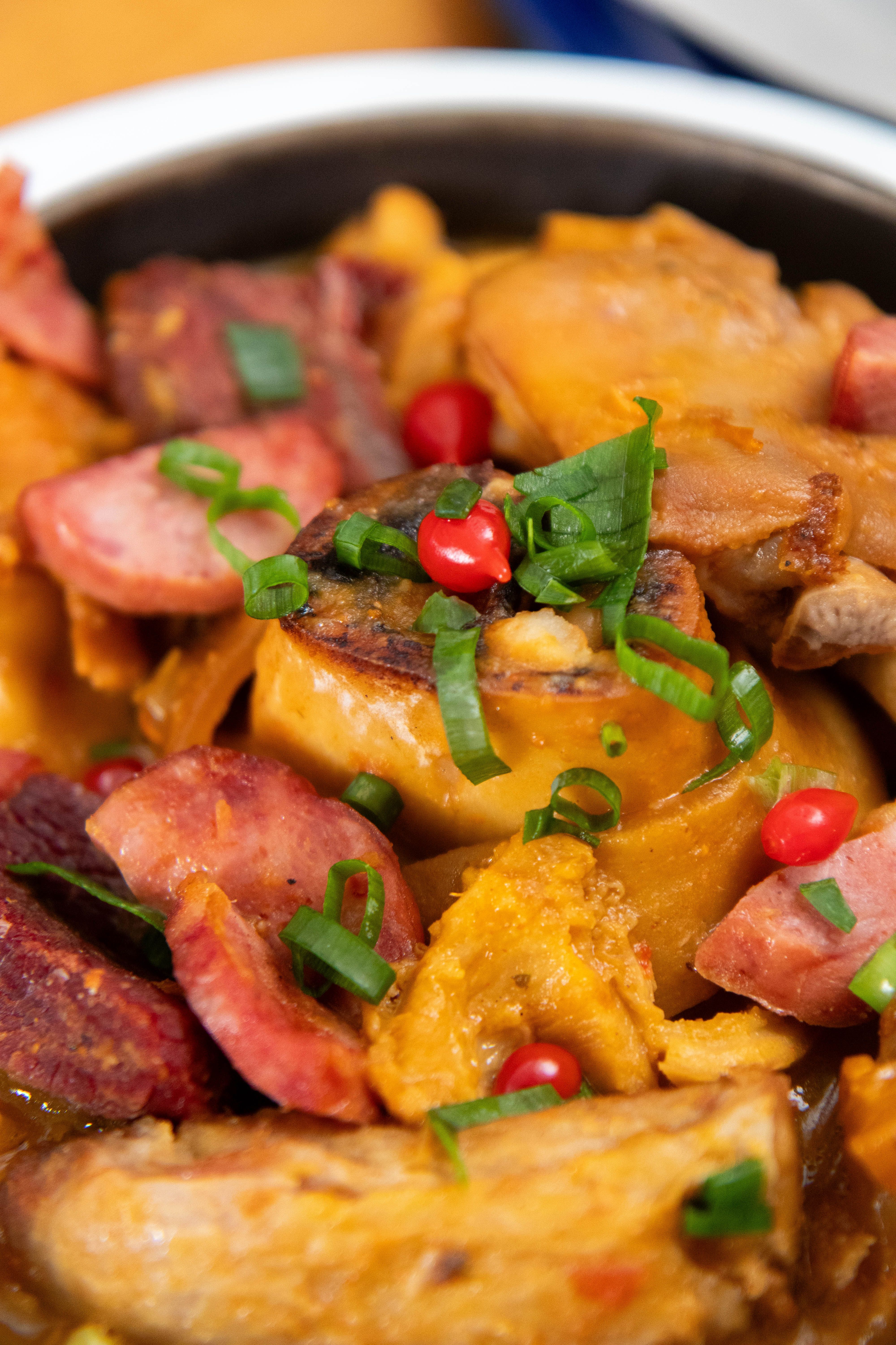 Close-up of a traditional Brazilian feijoada dish with sausage, beans, and fresh herbs, perfect for hearty meals.