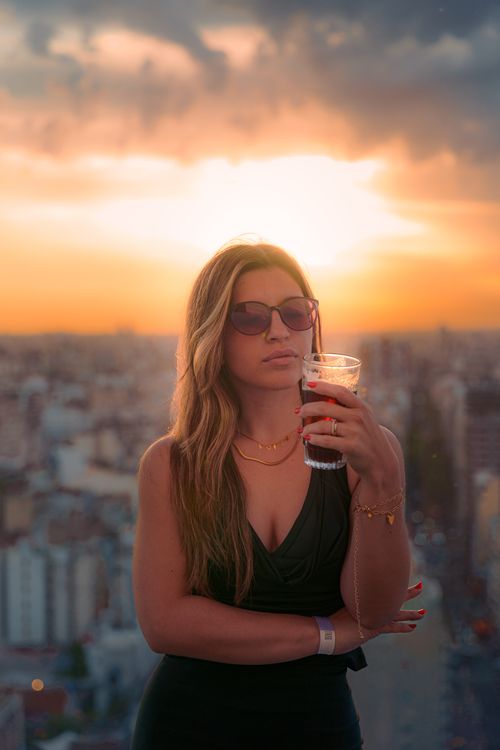 Stylish Woman Enjoying Sunset with a Drink · Free Stock Photo