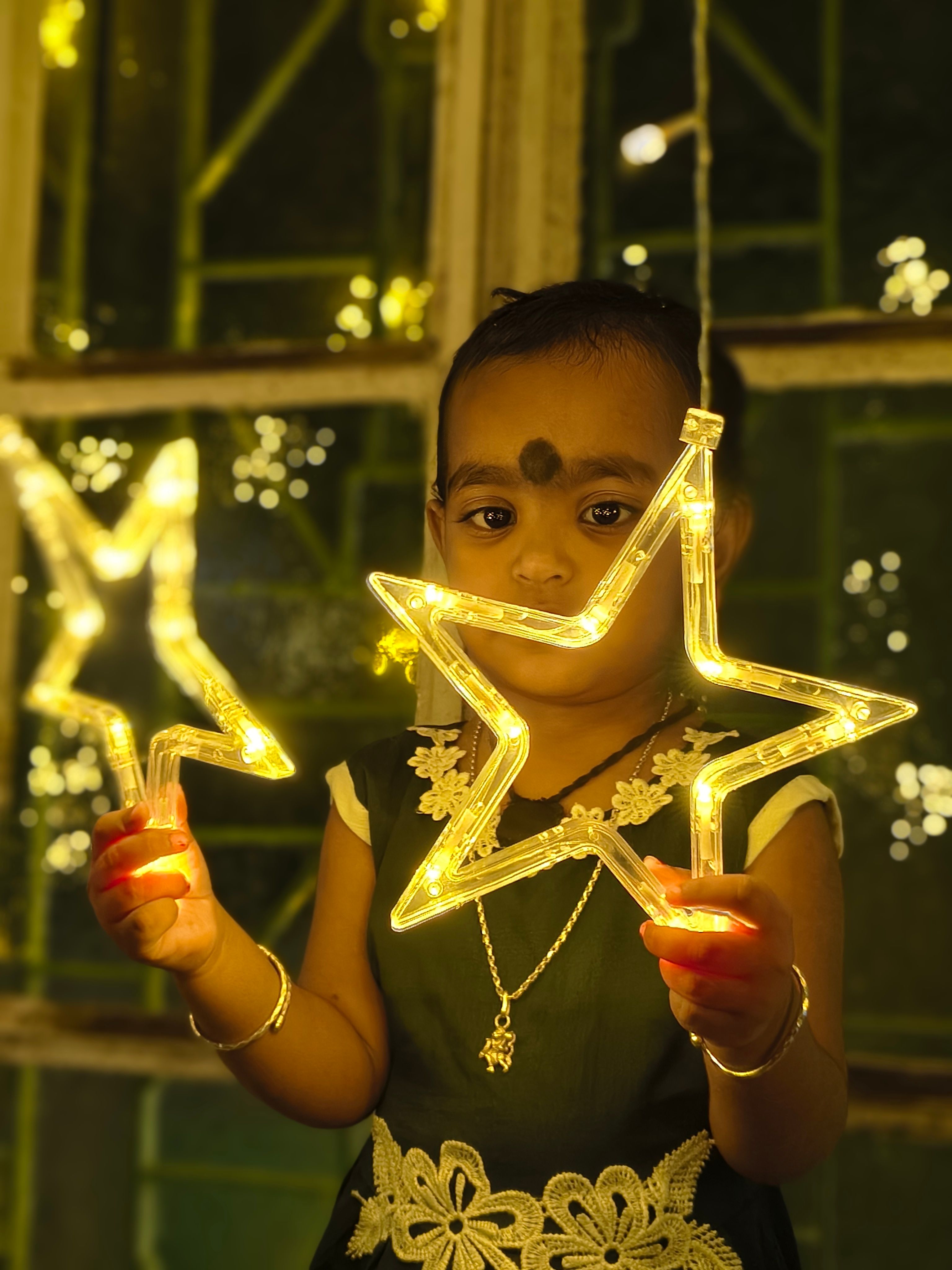 A young child holding star-shaped LED lights with a warm festive ambiance.