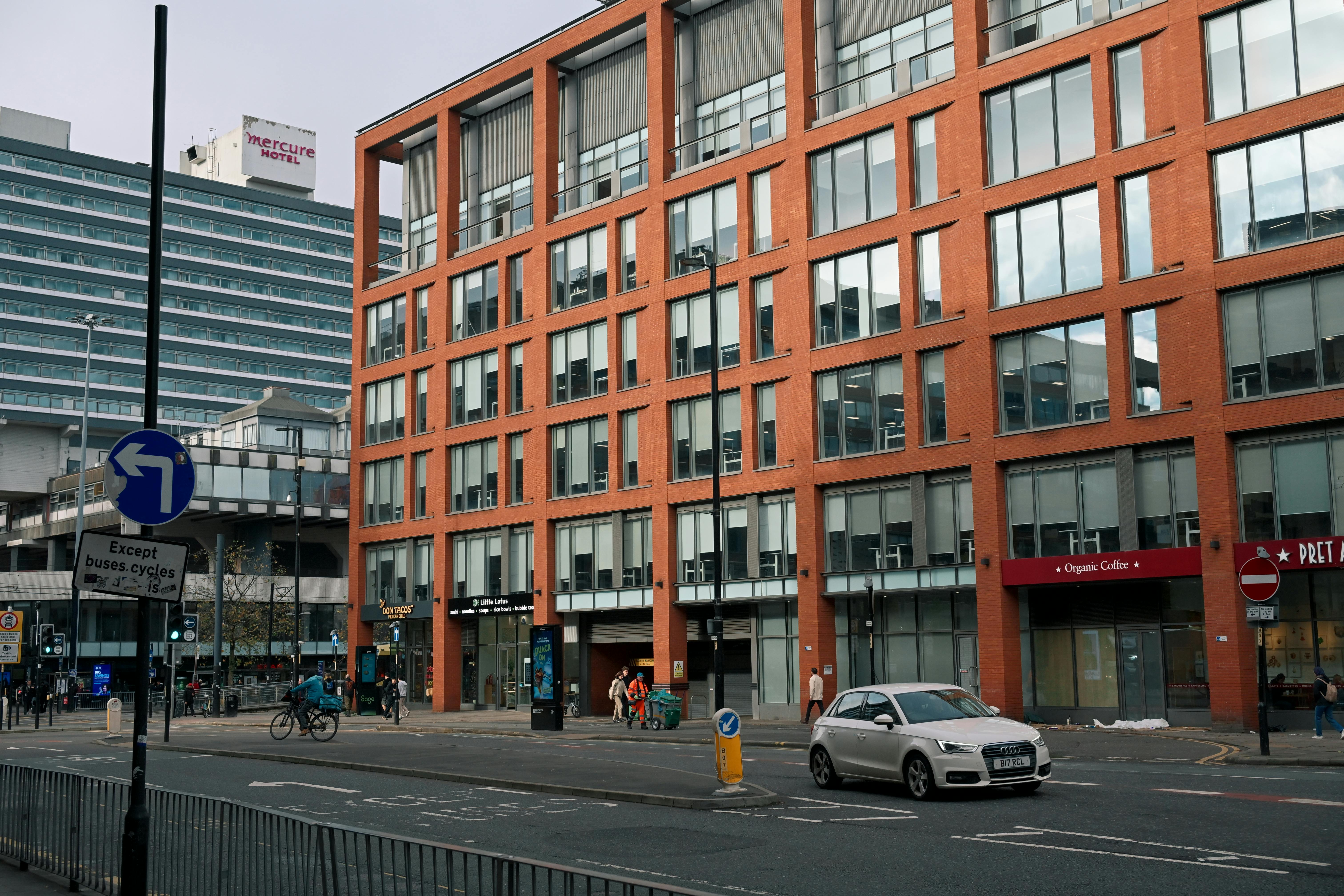 Street view of a modern city with brick and glass buildings and busy traffic.