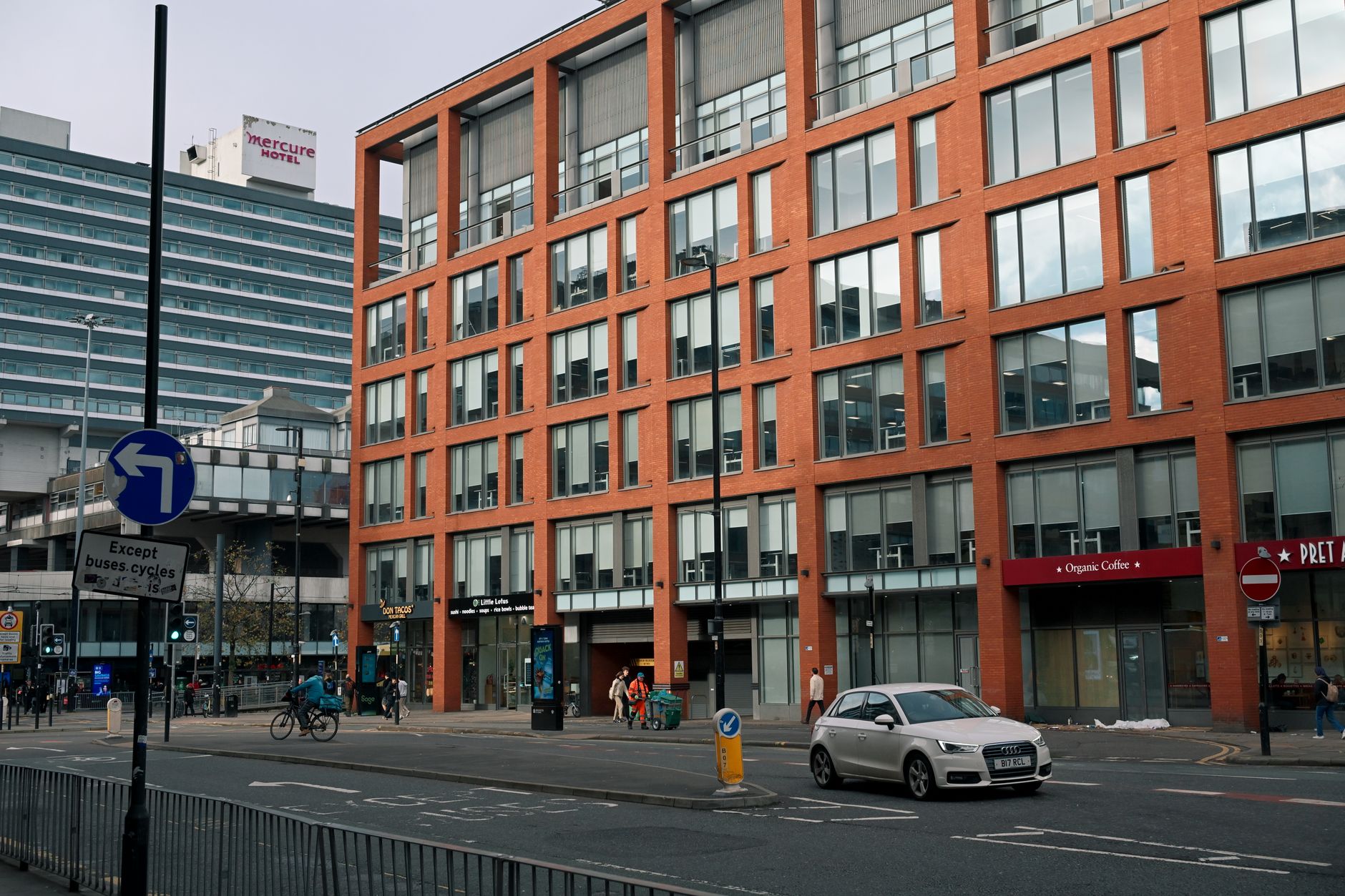 Street view of a modern city with brick and glass buildings and busy traffic.