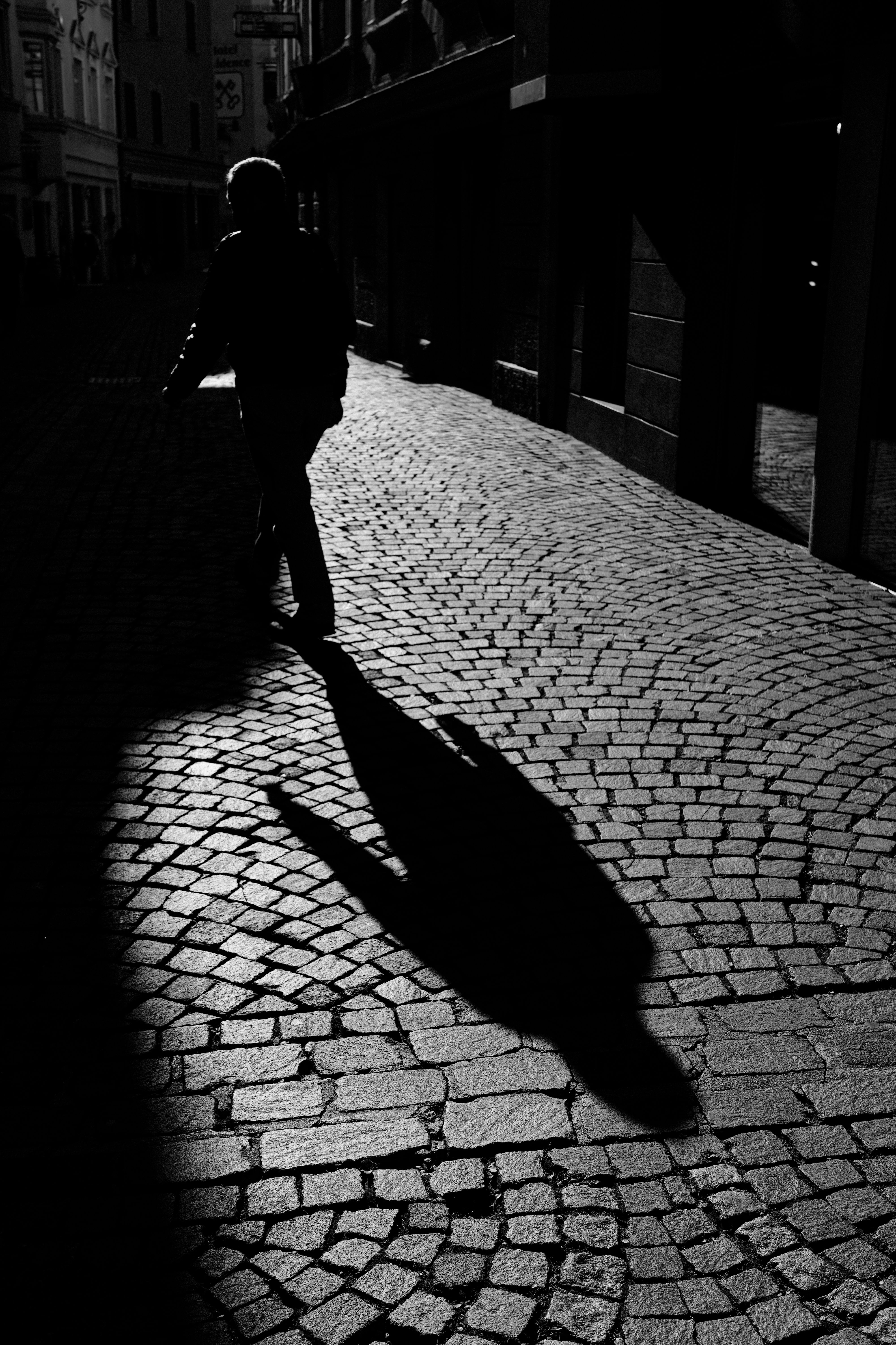 Silhouette of Person Walking on Cobblestone Street · Free Stock Photo