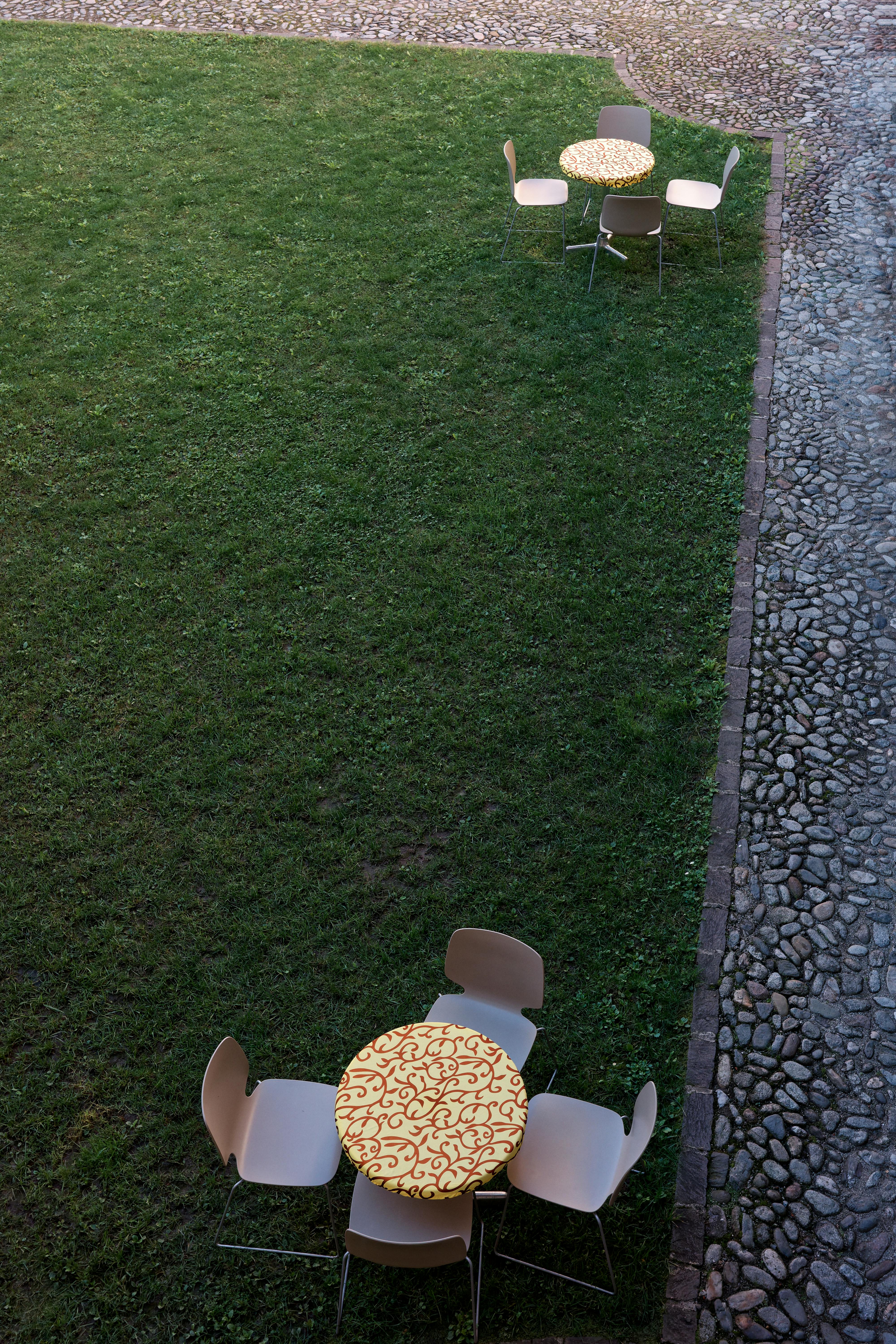 Aerial view of tables and chairs on grass beside a cobblestone path.