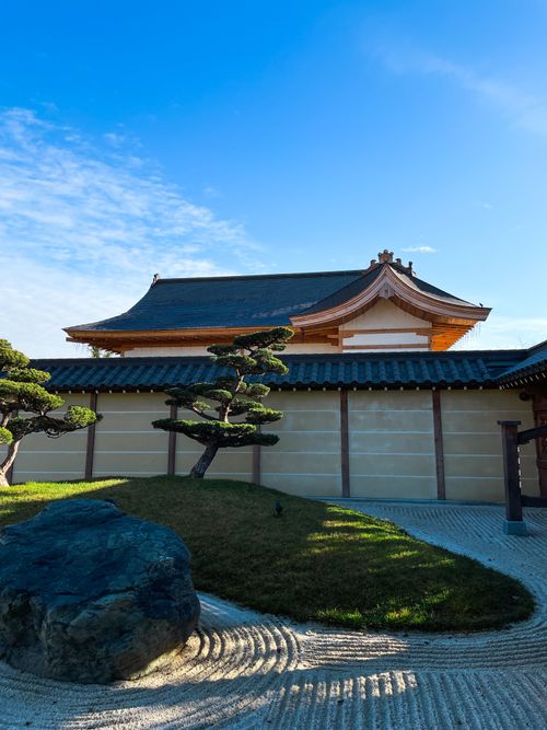 Free Serene traditional Japanese zen garden with temple and blue sky. Stock Photo
