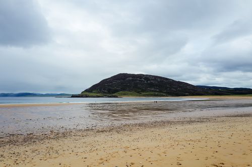 Free A tranquil beach with distant hills under an overcast sky, ideal for nature exploration. Stock Photo