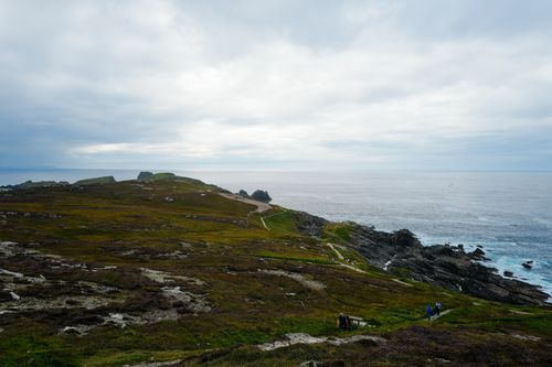 Free Expansive view of cliffside path leading to the ocean under a cloudy sky. Stock Photo