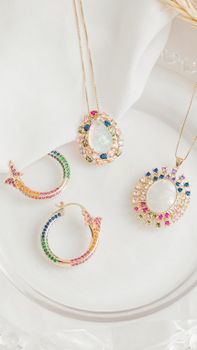 Sophisticated gemstone jewelry including pendants and earrings displayed on white fabric.