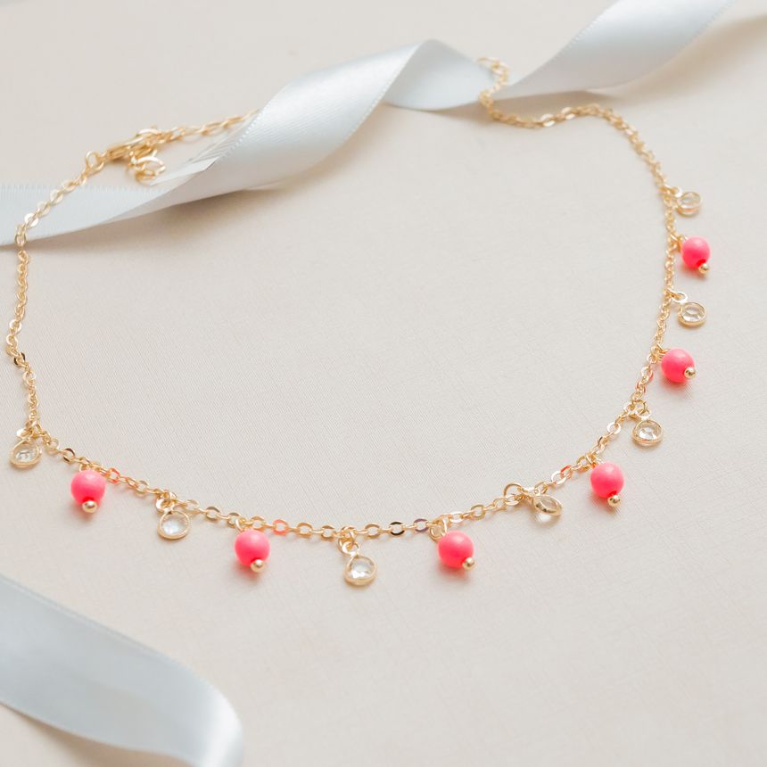 Coral bead and crystal charm chain on cream silk — photo by Laura Oliveira on Pexels