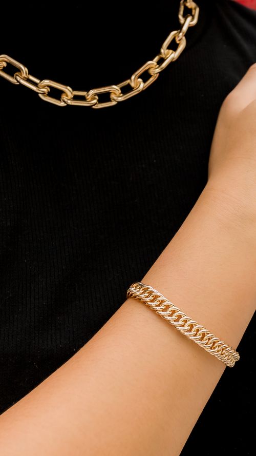 Free Luxurious gold chains adorning a person in a stylish black outfit, showcasing minimalistic elegance in fashion. Stock Photo