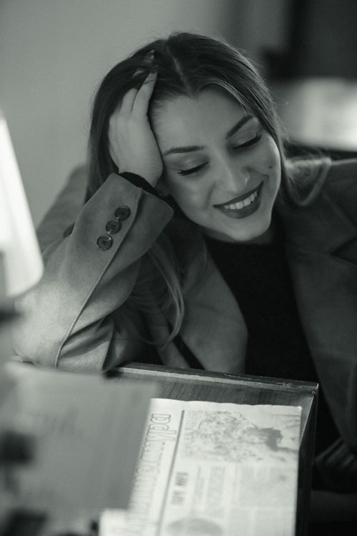 Free Elegant black and white portrait capturing a woman's genuine smile while relaxing in a cozy café. Stock Photo
